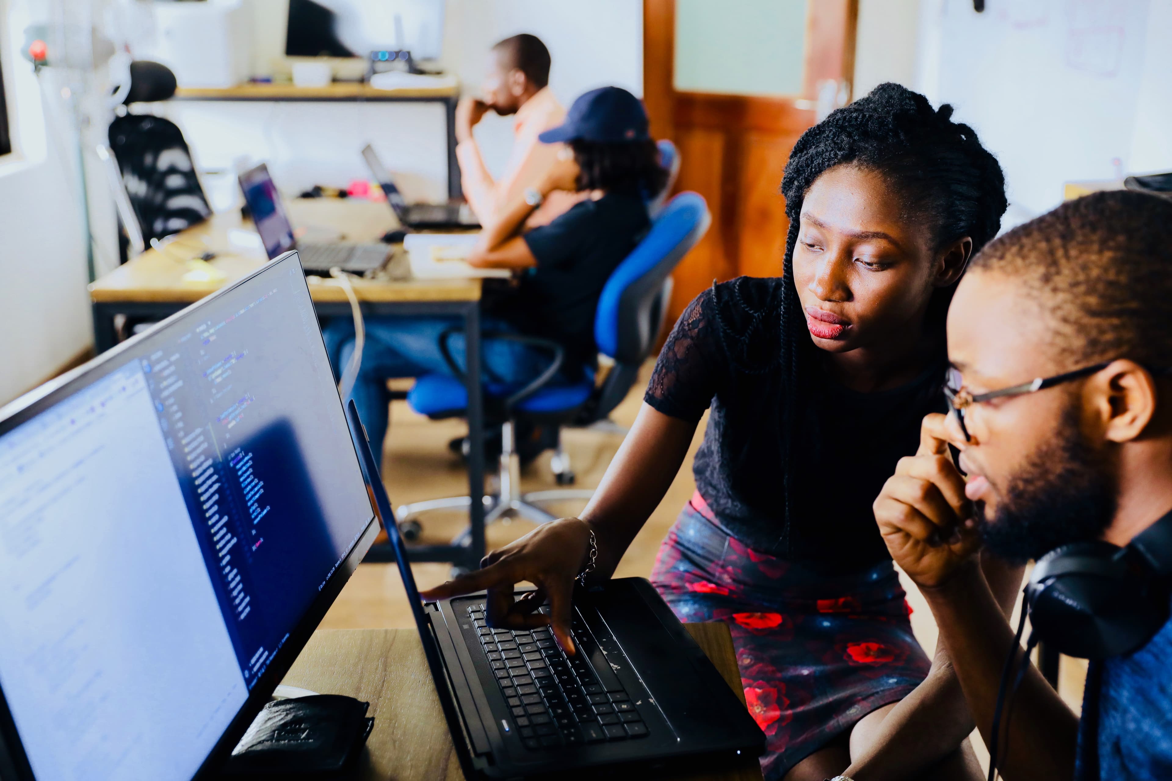 picture of a woman helping a man with a coding problem